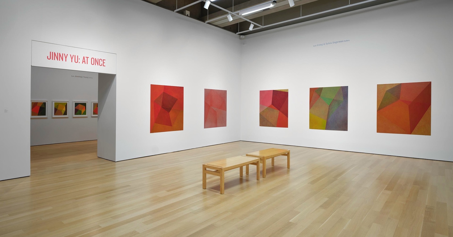 An art gallery exhibition space with whte walls and multicoloured abstract paintings.