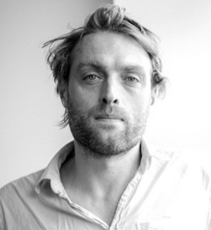 Félix wears a white button-up and has short, light-coloured hair.