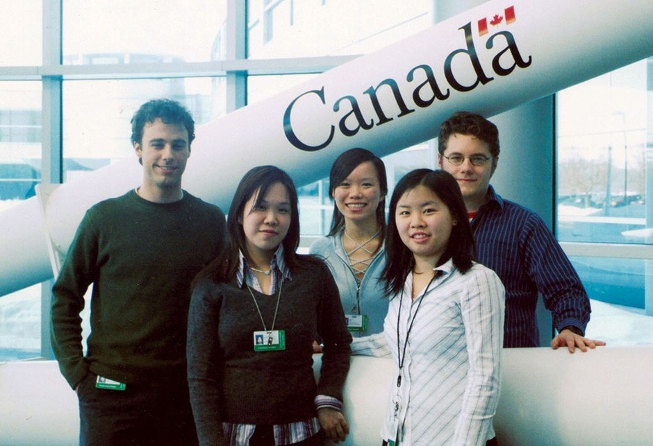 Five students stand in front of a life-size model of the Canadarm with the Canada logo imprinted on it.