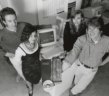 Four Concordia students stand around a computer and hold up an issue of Volute magazine and CD-ROM.