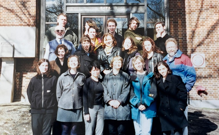 A group of students stands outside a brick building.
