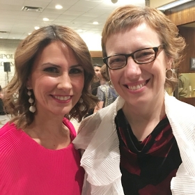 Two women are standing close together and smiling.
