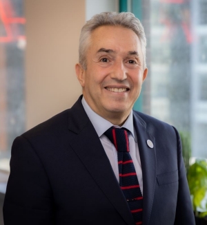 He wears a navy suit, a pale blue shirt and a red and navy striped tie.