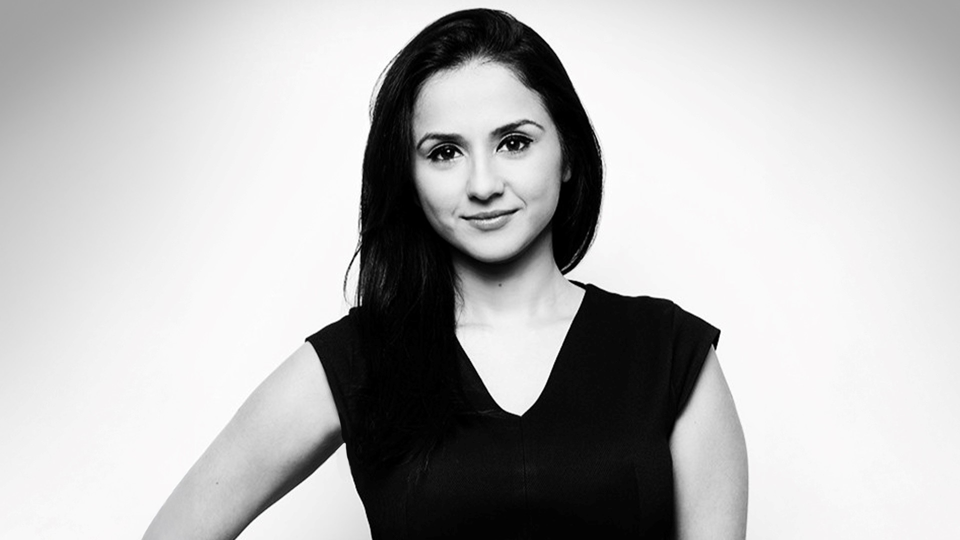 Rabia Khan A black and white headshot of Rabia. She has long, black hair and is wearing a black v-neck T-shirt.