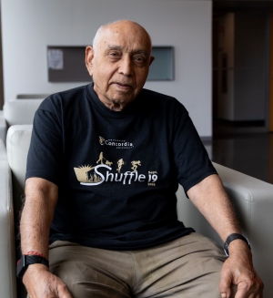Man sits on armchair wearing a Shuffle 19 t-shirt.