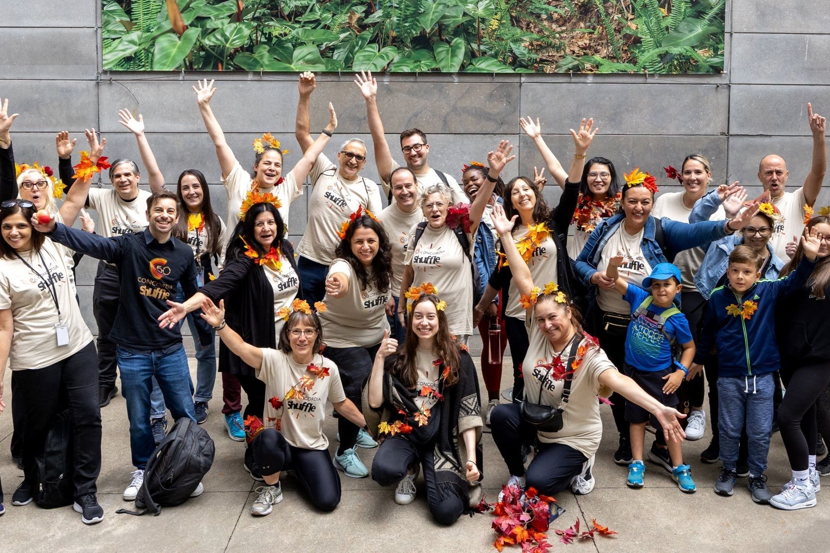 HR Shufflers Large group of people in beige shirts pose with autumnal leaves.