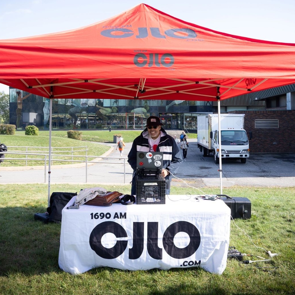 CJLO booth at Shuffle 2025 A deejay stands behind his equipment on a table outside.