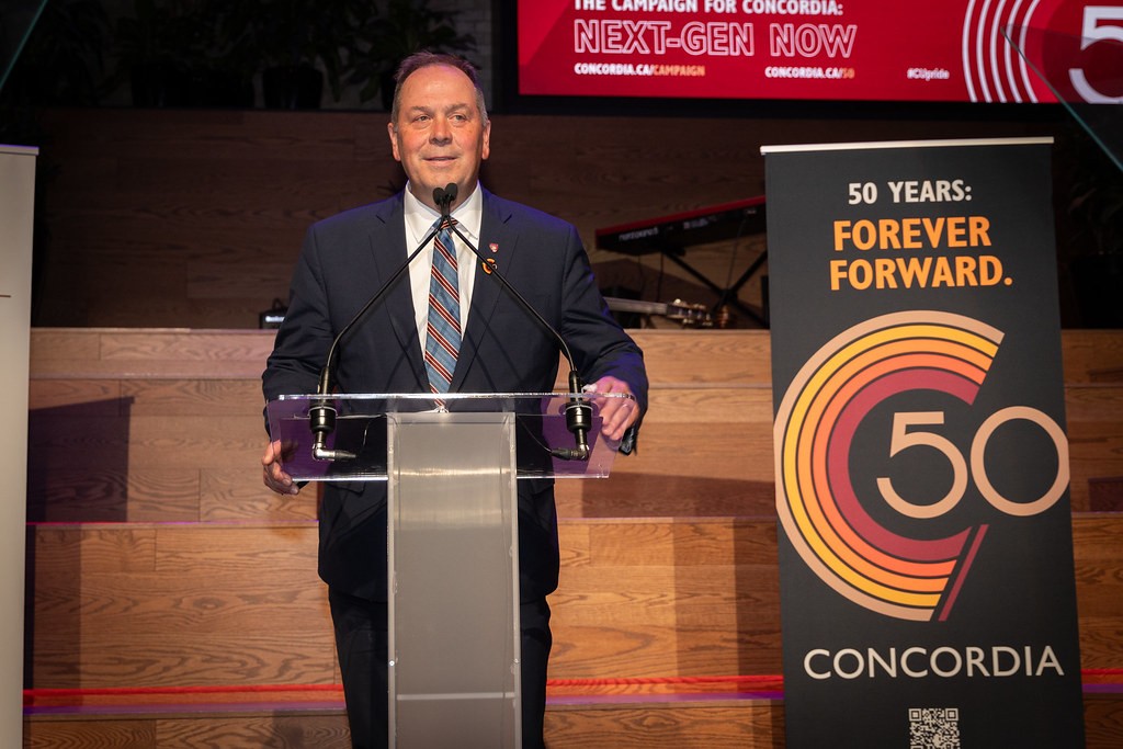 Man wearing a suit speaks at a podium.
