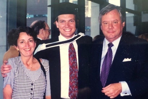 Group photo of aunt and uncle standing next to either side of nephew at convocation.