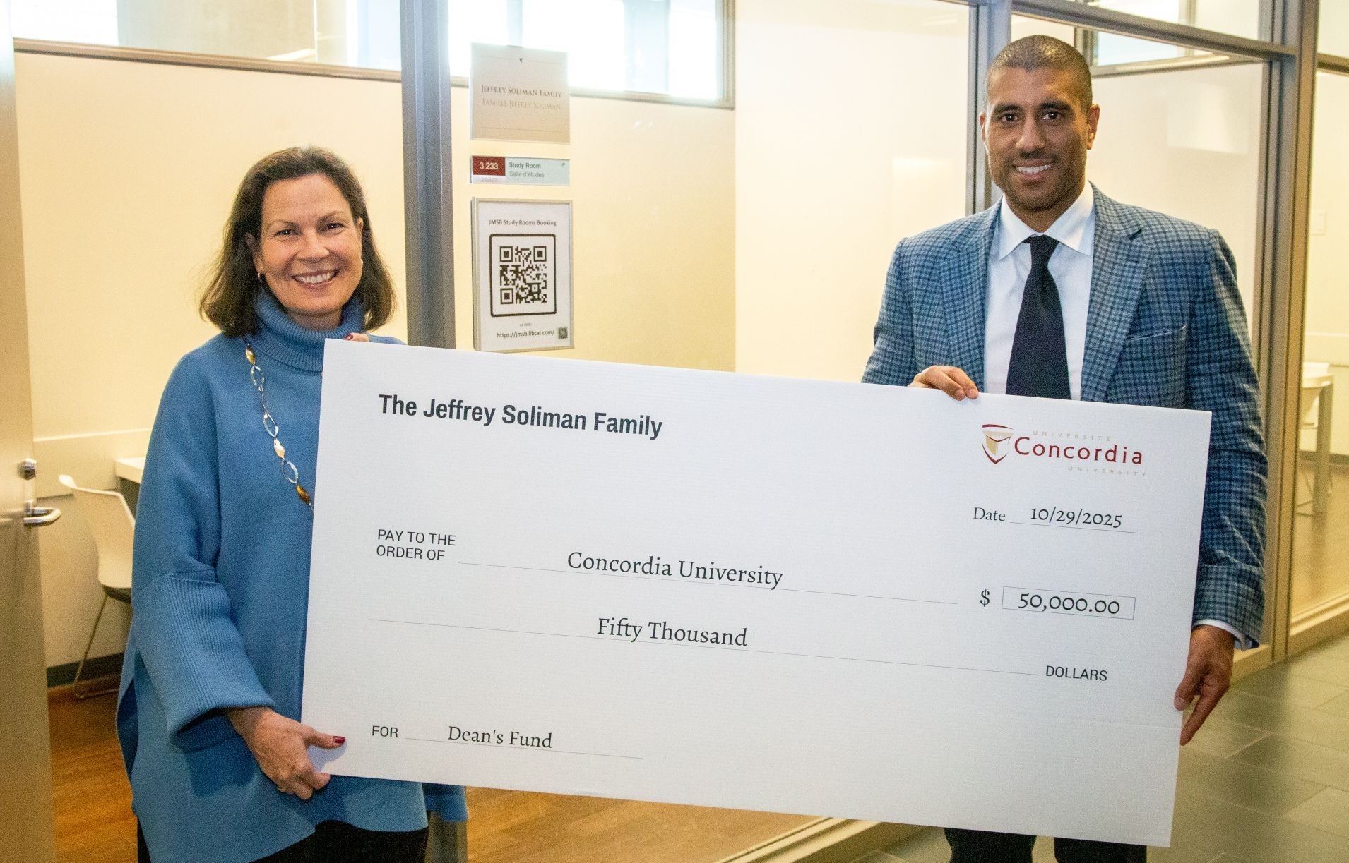 Woman with dark hair and blue sweater and man wearing checkered jacket hold a giant cheque payable to Concordia in the amount of $50,000, from the Soliman Family.