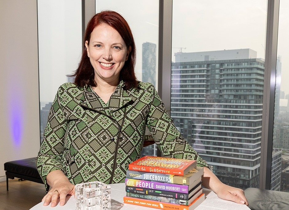 Jennifer stands at a table with a stack of books in front of her.