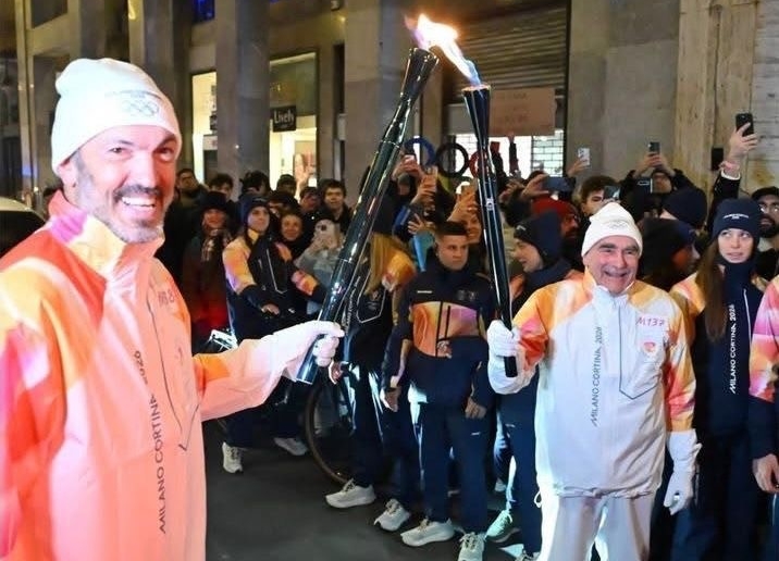 The Olympic flame transfers between the torches of two torch bearers. 