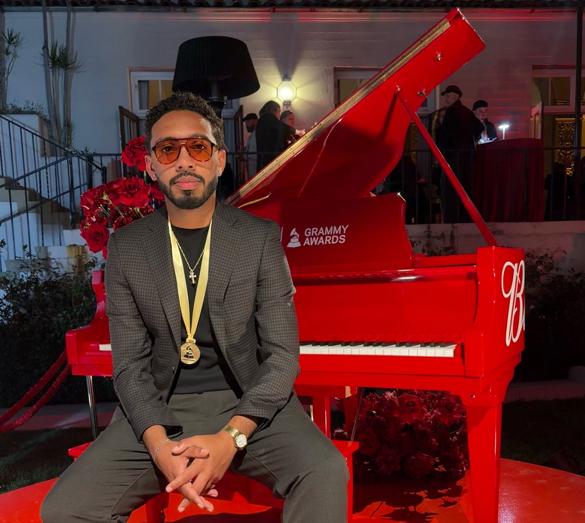 Chase sits at a a red grand piano.