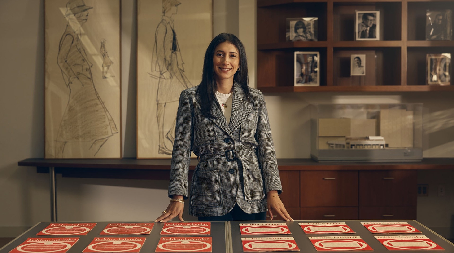 Natalie stands behind a table that has copies of the Fashion Calendar spread evenly across it.