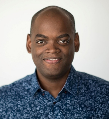 Man wearing blue printed shirt looks into camera