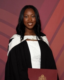 Tatiana Auguste poses in her graduation gown and hold her diploma.