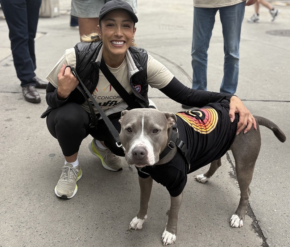 Nura Jabagi poses with her dog Bubbles outside. They are both wearing Concordia University t-shirts.