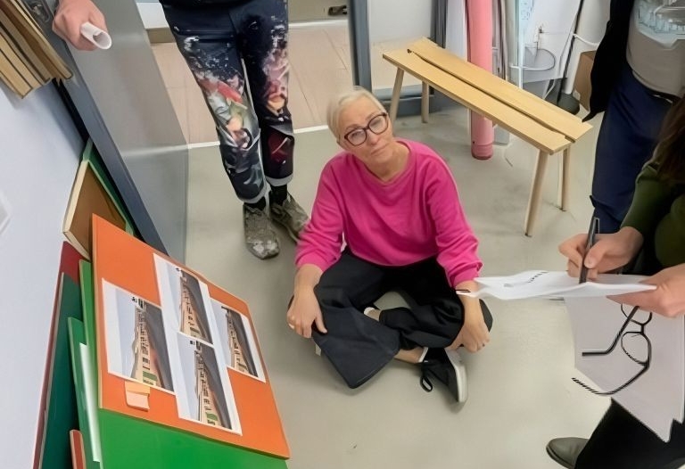 Élise sits one the floor and is surrounded by her team members looking at colourful swatched and story boards.
