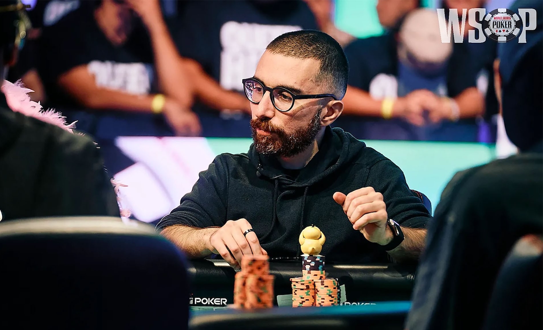 Rami sits at a table with a stack of poker chips in front of him.