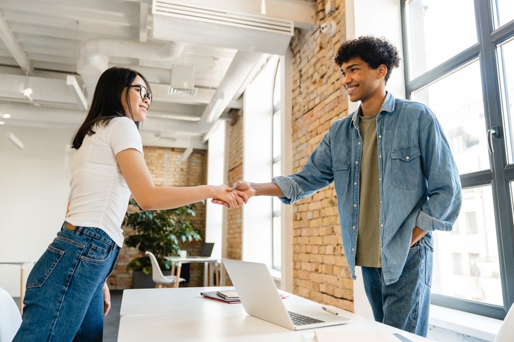 A woman and man shake hands at work