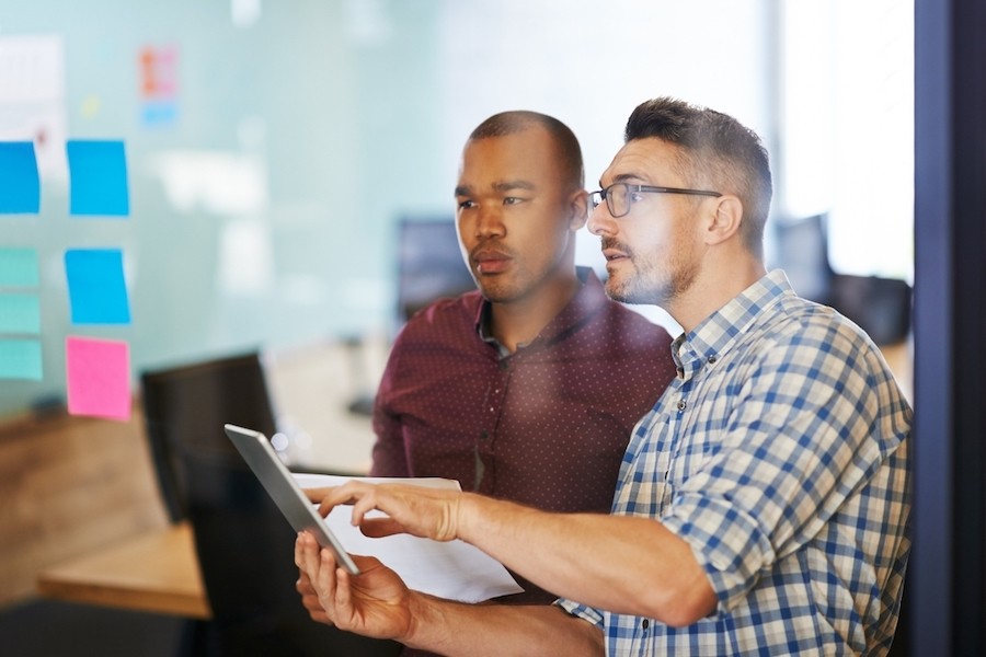 Two male colleagues work on a tablet