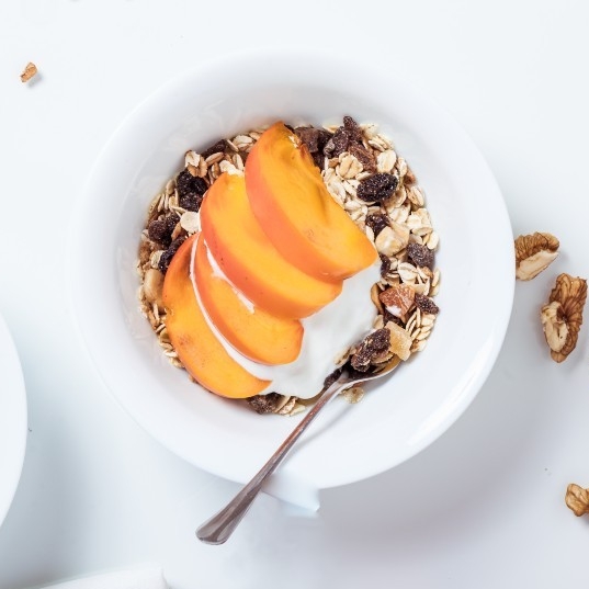 A bowl of granola with peach slices