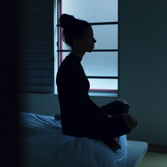 Silhouette of a sleepless woman sitting on a bed