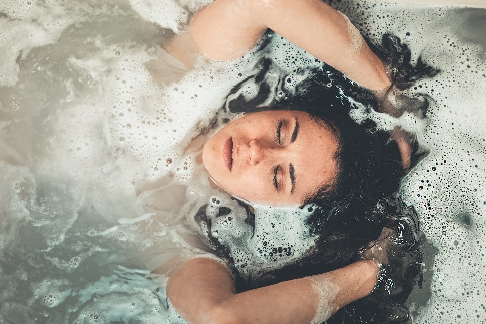 Brunette woman relaxes in a bubble bath