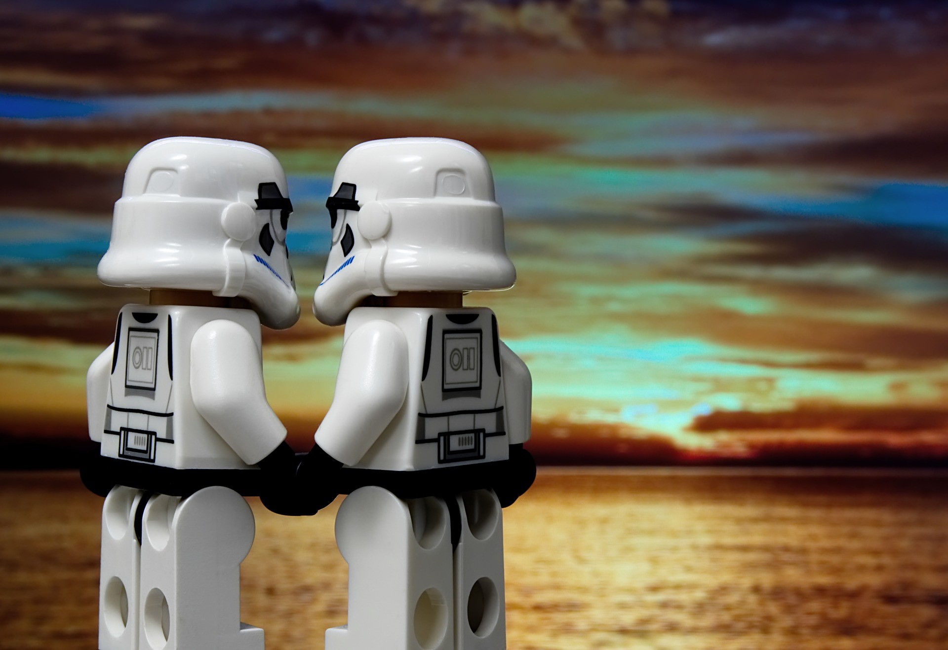 Two Lego stormtroopers holding hands and looking at the sunset