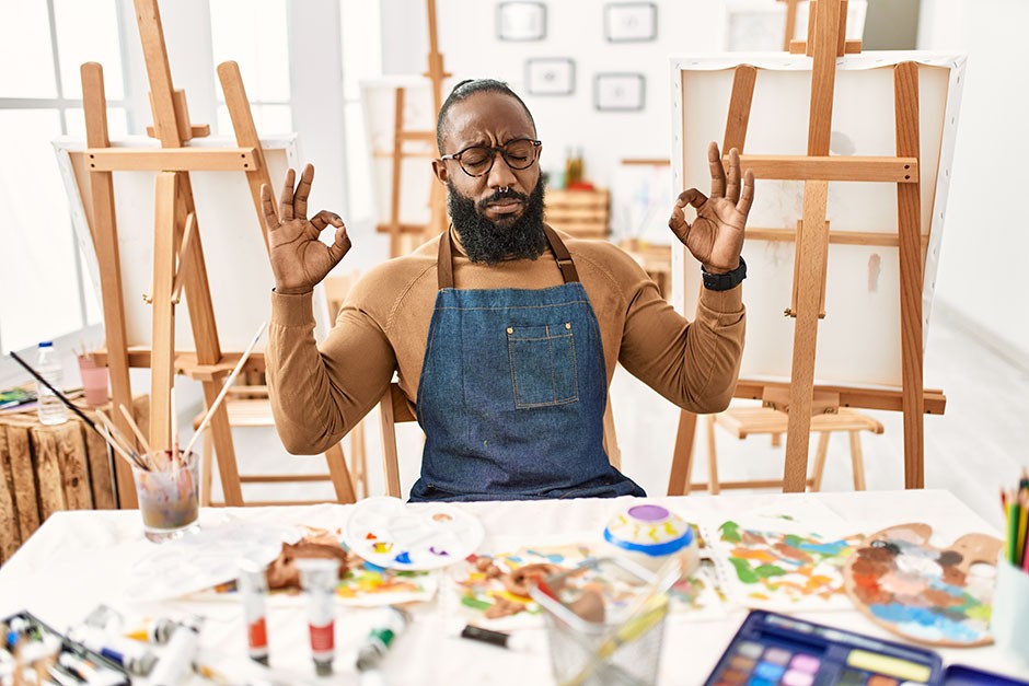 Black male artist de-stressing through meditation in art studio