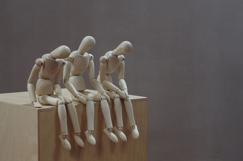 Three wooden mannequins sit and talk