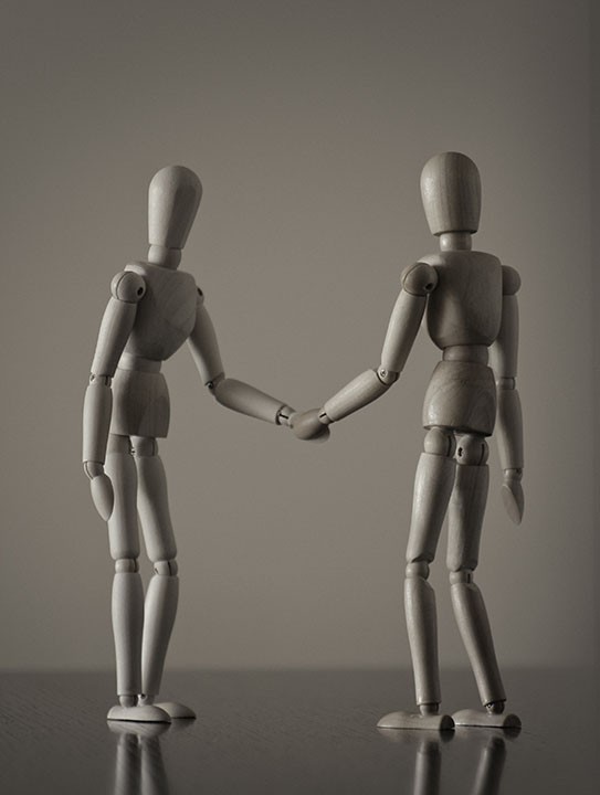 Two wooden mannequin handshakes