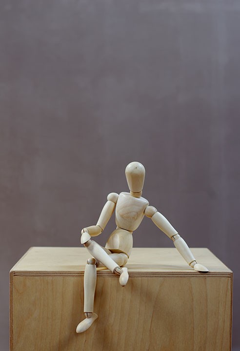 Wooden mannequin sits confidently