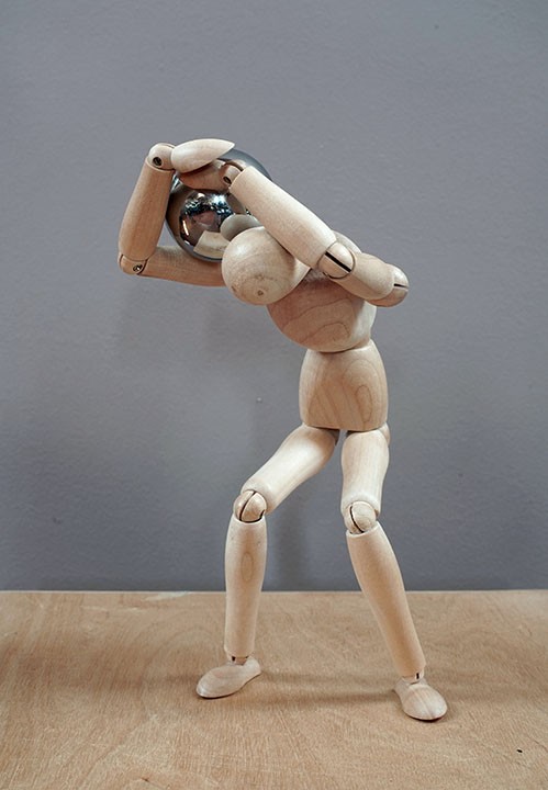 Wooden mannequin carries a heavy object