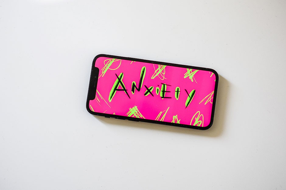 An iphone showing a pink illustration that says “anxiety” 