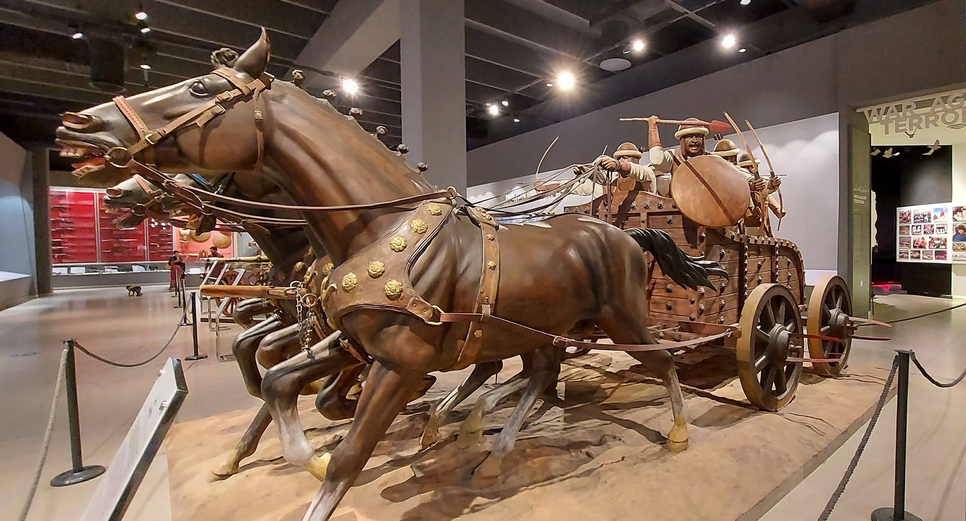 A chariot with brown horses and men carrying spears and arrows. 