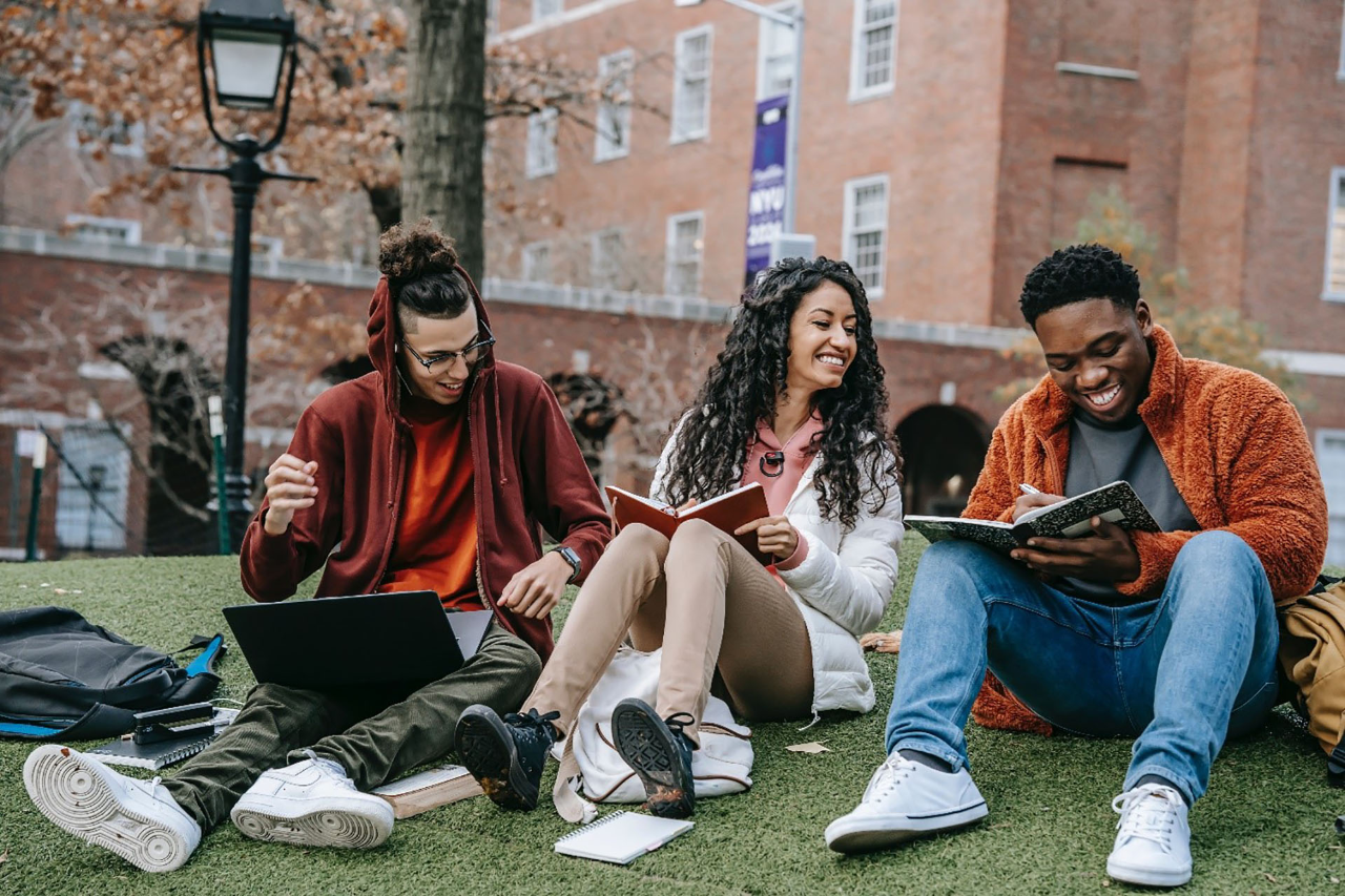 A multiethnic group of students with books sitting near university