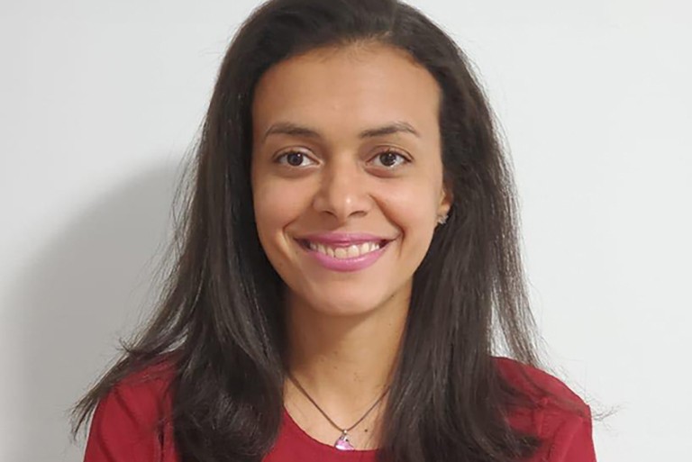 Jeune femme souriante aux longs cheveux noirs et une chemise rouge.