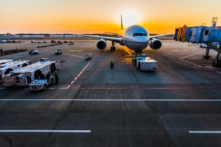 Grey airplane parked at gate during sunset