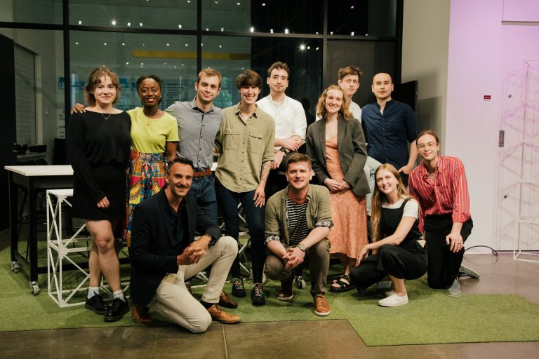 Photo de groupe de 12 personnes souriantes, certaines debout et d'autres à genoux