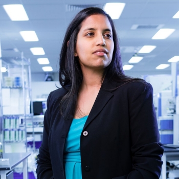 Woman with long dark hair standing in a lab.