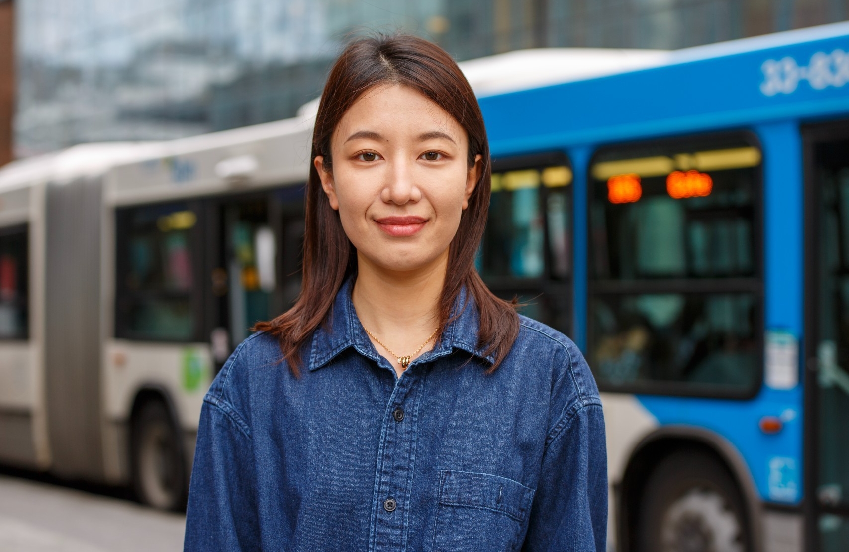 Xuelin Tian porte une chemise bleue devant un bus de la ville de Montréal.
