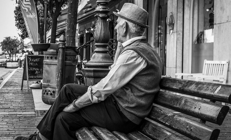 Elderly man sits on a bench