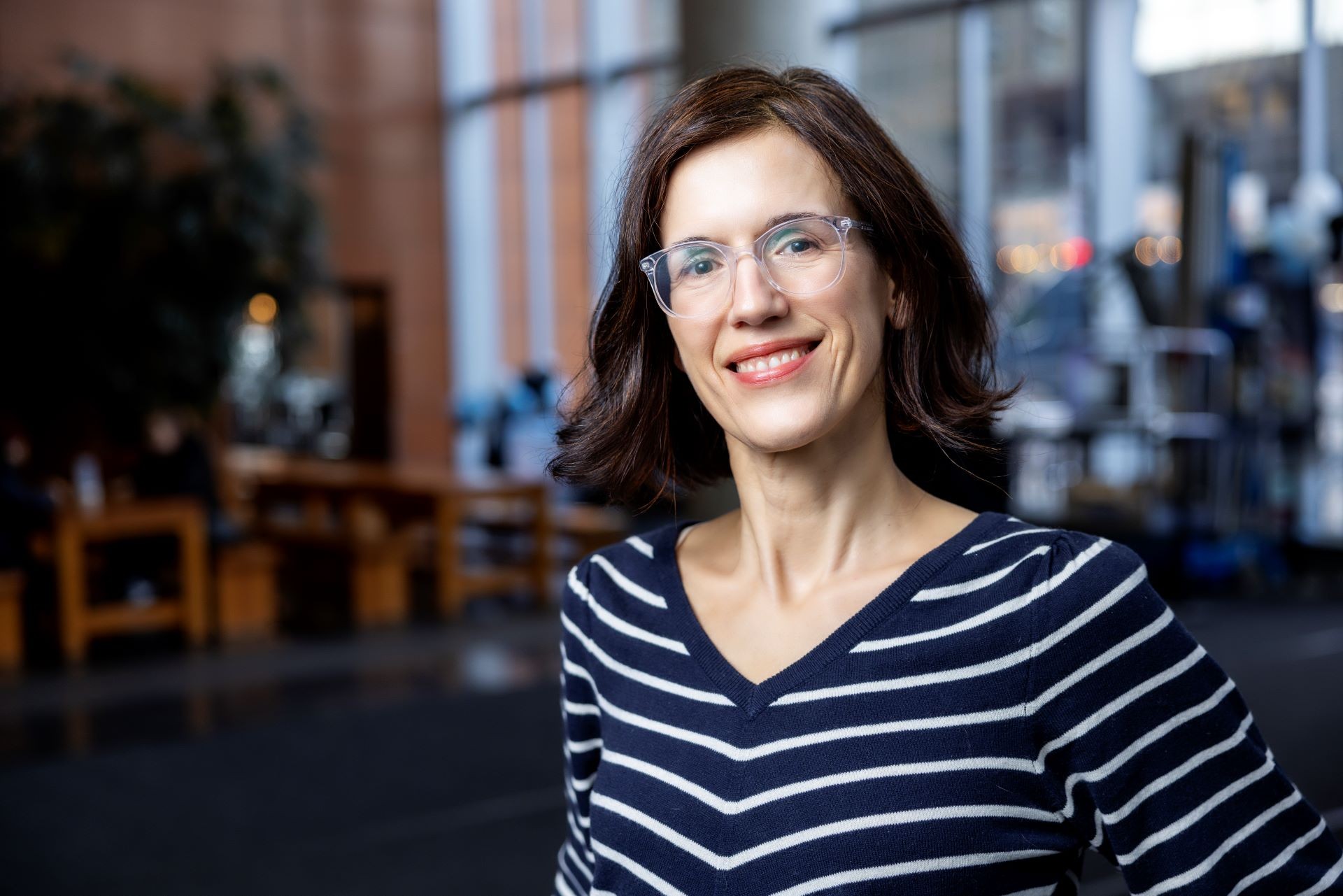 Claudine Mangen a les cheveux noirs jusqu'aux épaules et porte une chemise bleue et blanche à rayures horizontales.