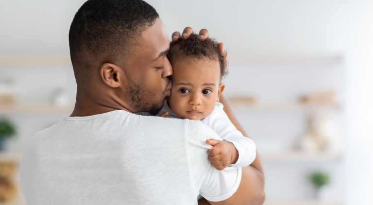 Un homme en tee-shirt blanc berce sa petite fille.