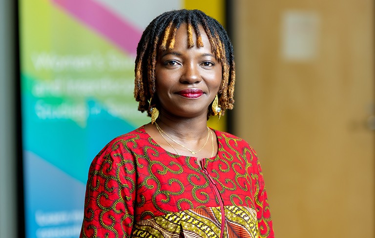 Abena Kyere A young smiling woman with braided hair and red and yellow patterned top