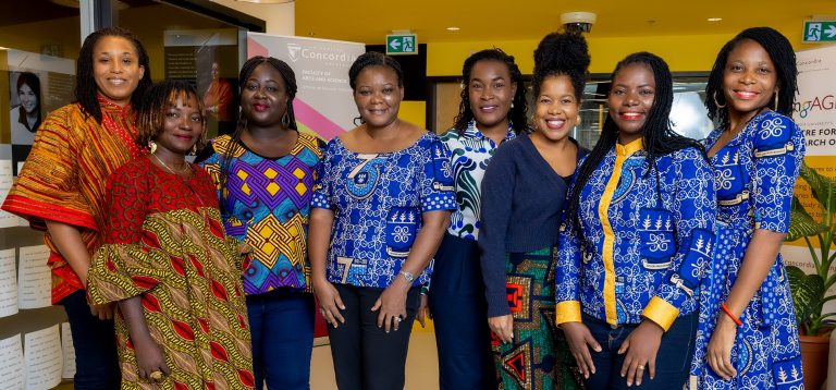 Un groupe de femmes debout ensemble dans un décor intérieur et souriant devant la caméra