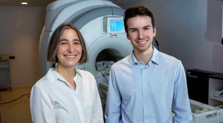 Deux chercheurs se tiennent devant un appareil d'IRM.