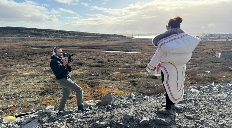 L’attaché de recherche en journalisme de Concordia Luca Caruso-Moro photographie Aleashia Echalook, directrice d’Ajurisarvik et mère de trois enfants, à côté de sa maison, à Inukjuak. Dolly, sa petite de trois mois, est lovée dans l’amauti de sa mère, un parka traditionnel porté par les femmes inuites. | Photo : Aphrodite Salas