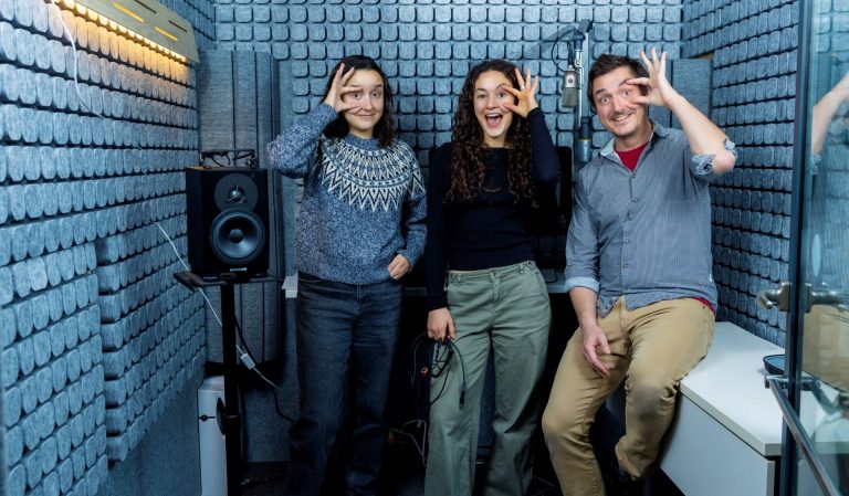 Trois chercheurs dans un laboratoire audiovisuel gardent leurs yeux ouverts en plaisantant. 